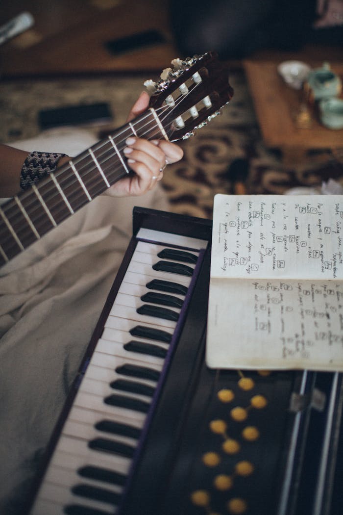 services-05 Close-up view of a guitar and keyboard with sheet music, capturing a cozy indoor music session.
